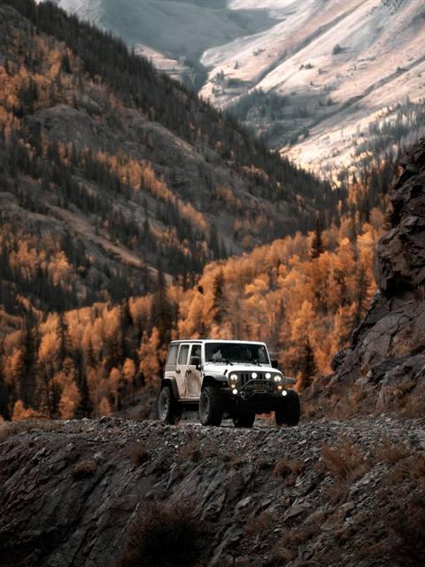 Jeep preparado en un camino de cornisa de piedra entre montañas