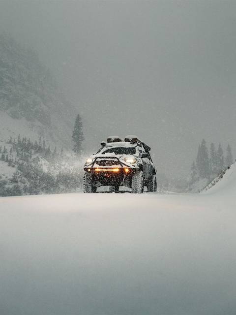 Camioneta 4×4 preparada con luces ámbar avanzando en una nevada